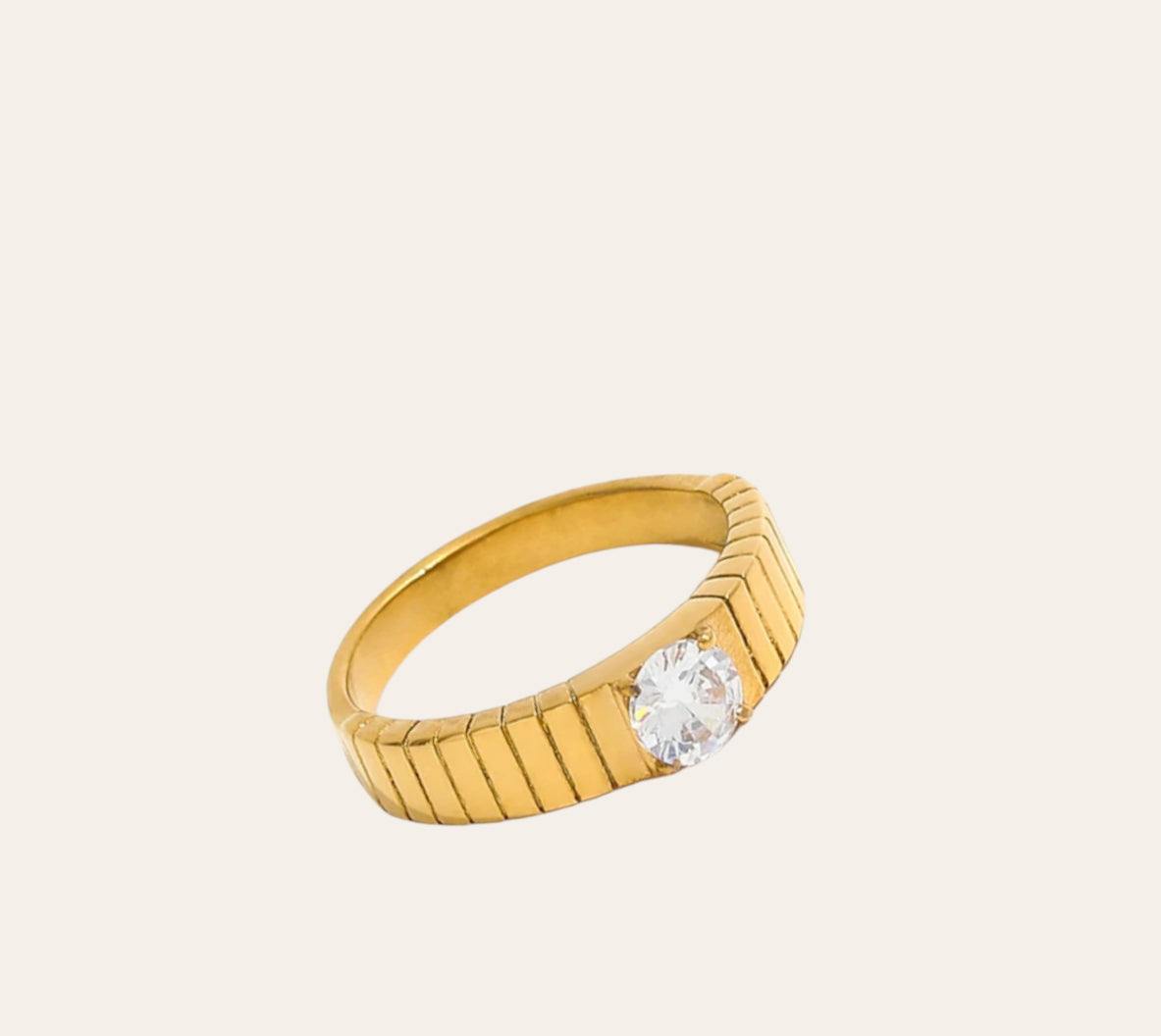 Adorn Ring, gold-plated ridged band with clear zircon solitaire on plain background