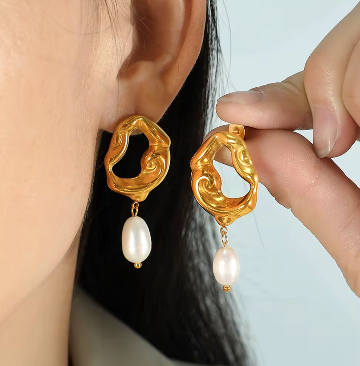 Gold sculptural earrings with flowing open design and dangling pearl drops.