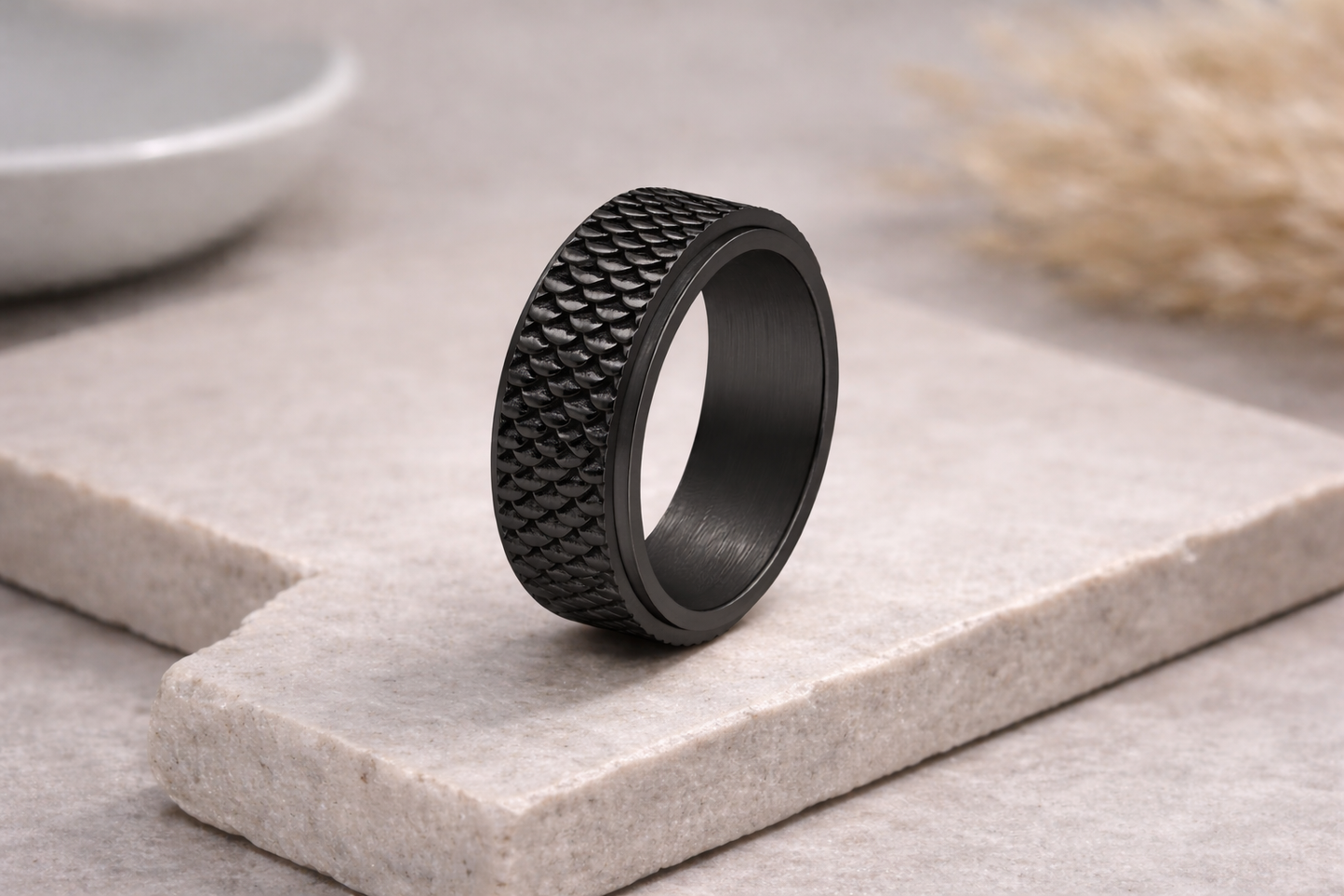 Black textured ring on a light stone surface with a blurred background