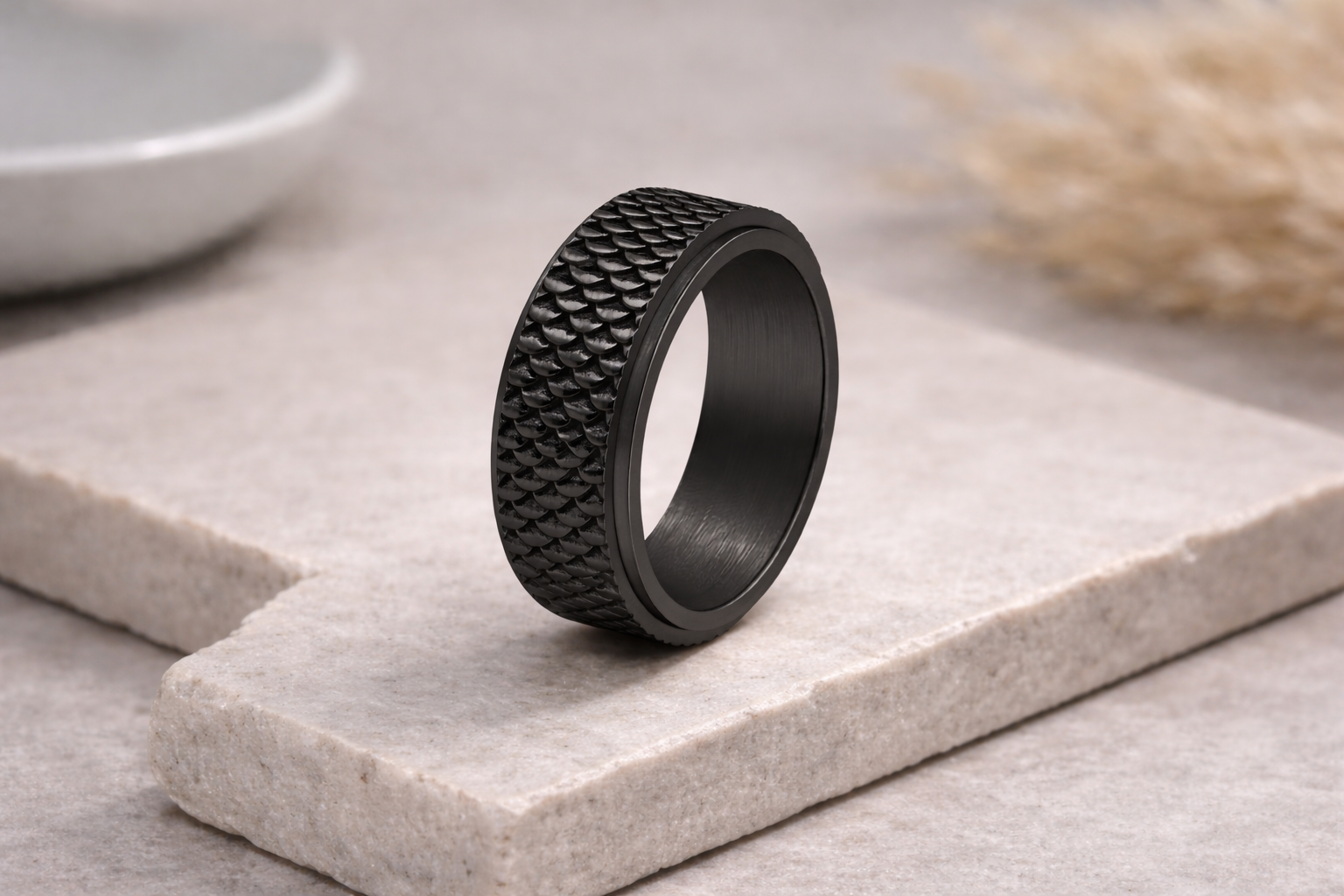 Black textured ring on a light stone surface with a blurred background