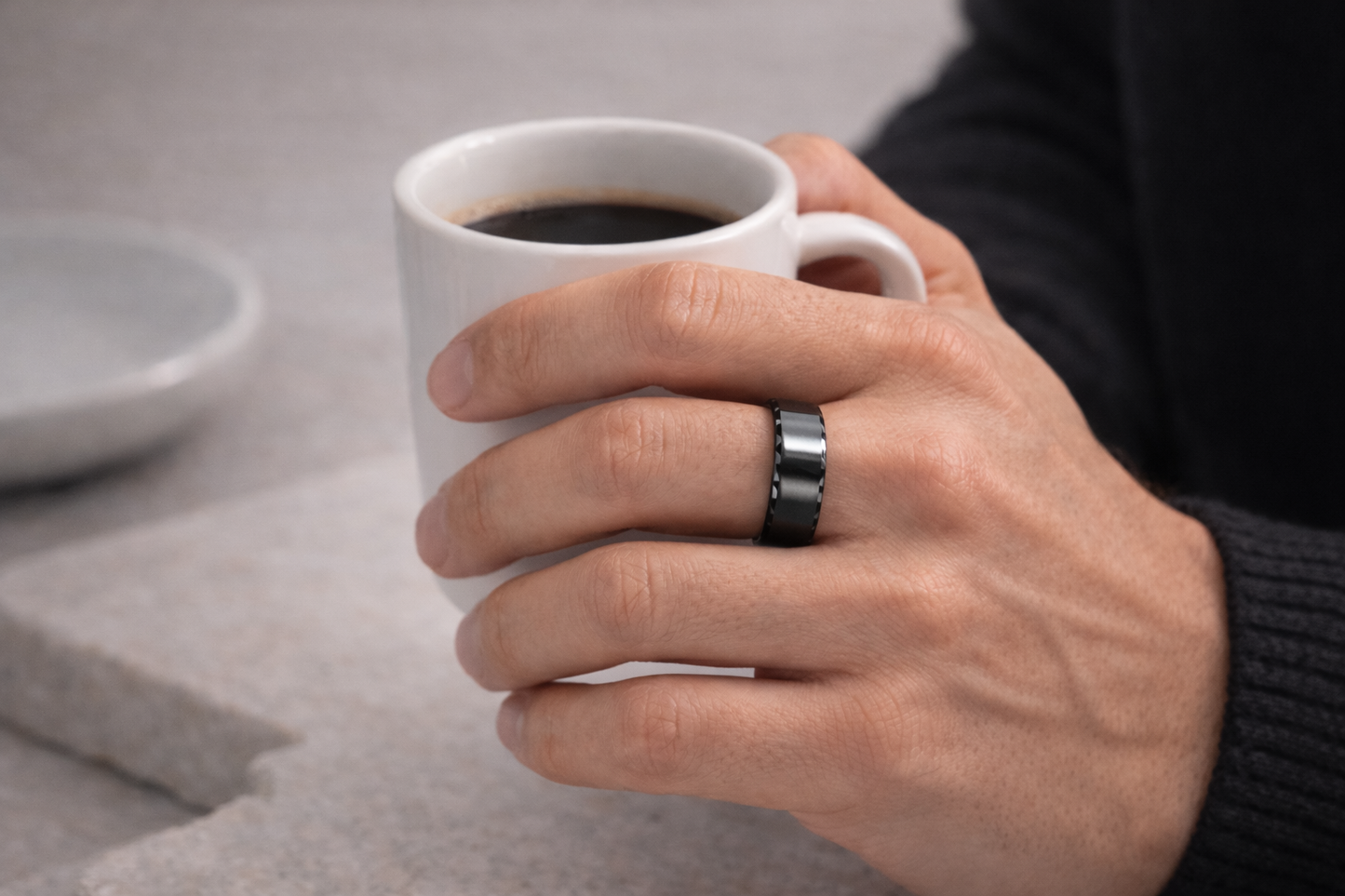 Hand holding a white mug with coffee on a neutral background