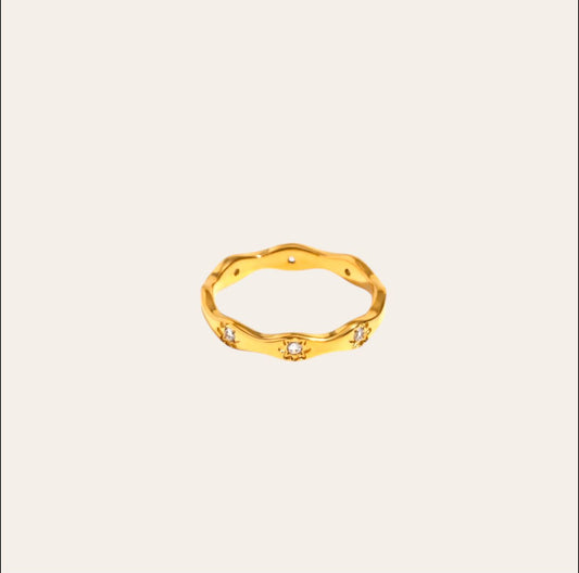 Astro Ring, wavy gold-plated band with starburst-set clear zircon on plain background