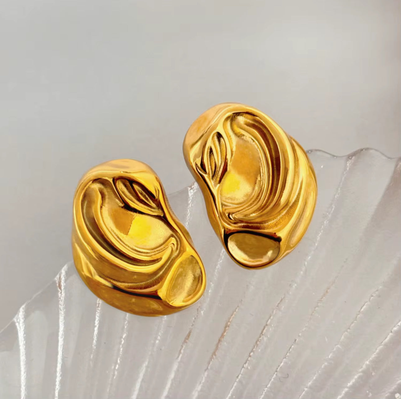 Gold sculptural earrings with fluid organic design and polished reflective surface.