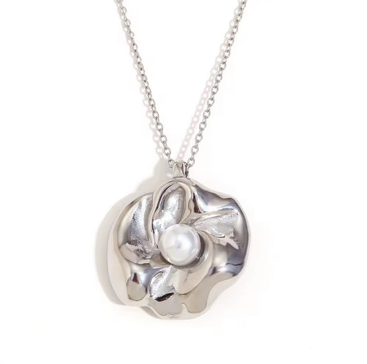 Silver floral pearl necklace with sculpted pendant and luminous pearl center on chain.