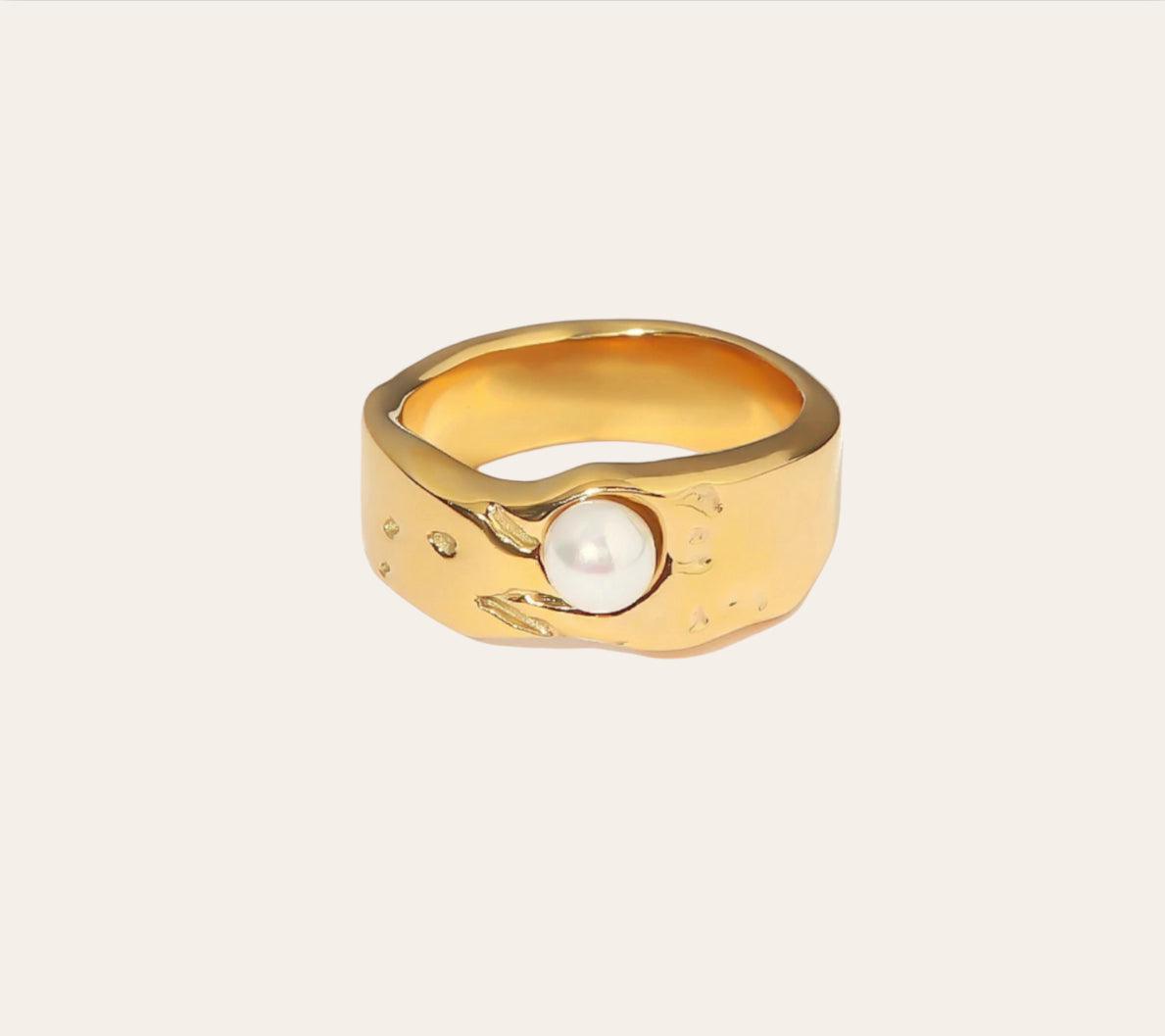 Jolly Ring, gold-plated sculpted band with bezel-set imitation pearl on plain background