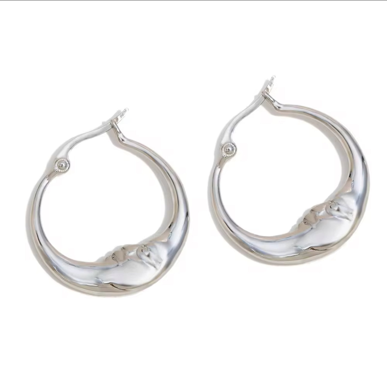Silver moon face earrings with sculpted artistic design and polished surface.