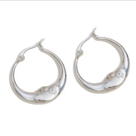 Silver moon face earrings with sculpted artistic design and polished surface.