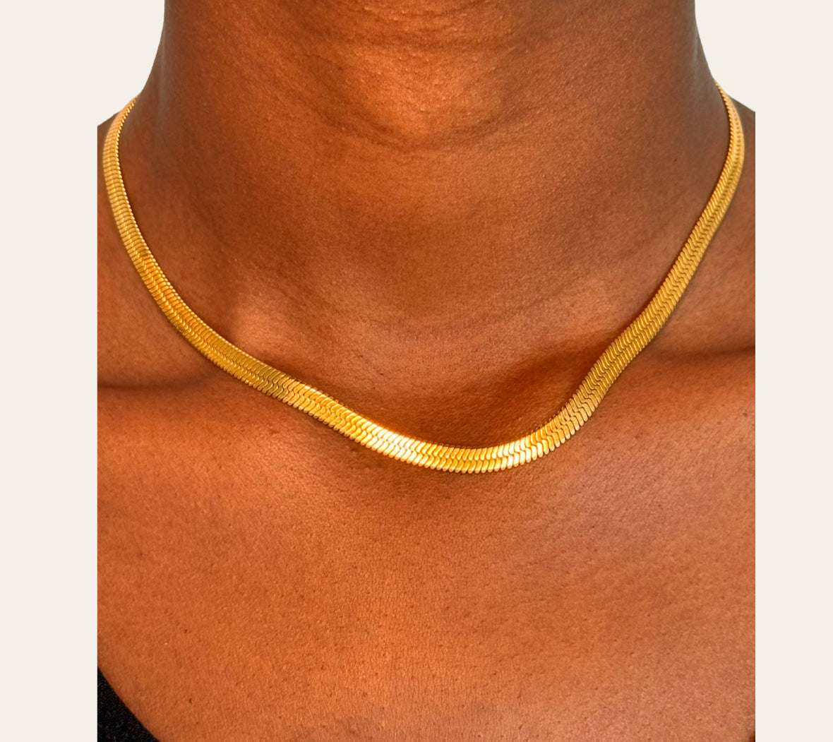 Model wearing Snake Chain necklace in gold variant, close-up on neckline.