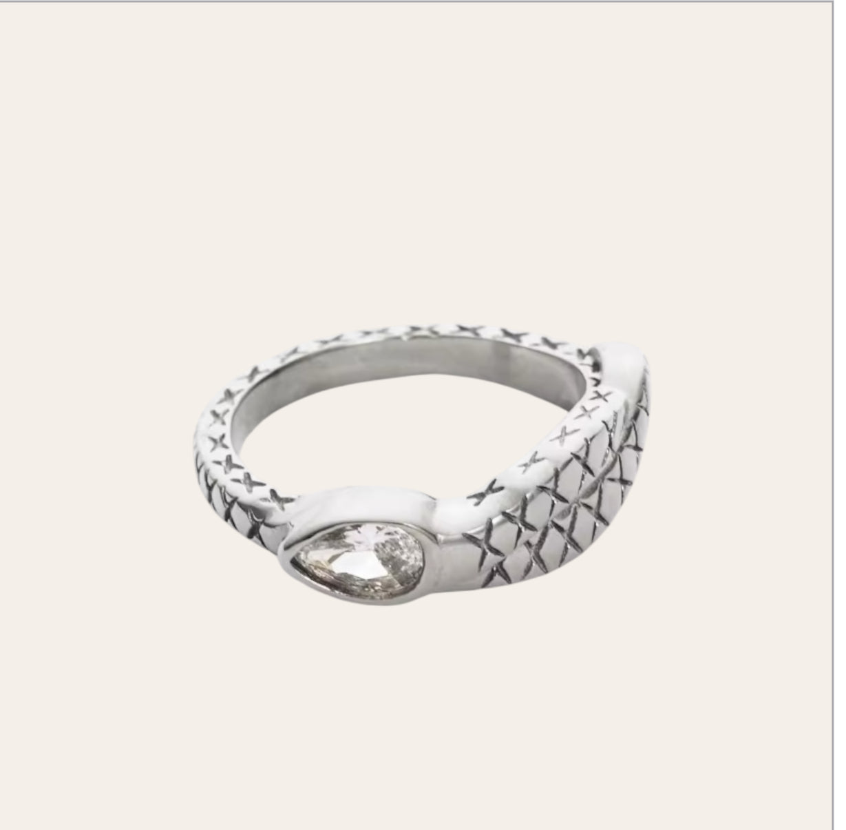 nake Ring in polished stainless steel with clear zircon on plain background.