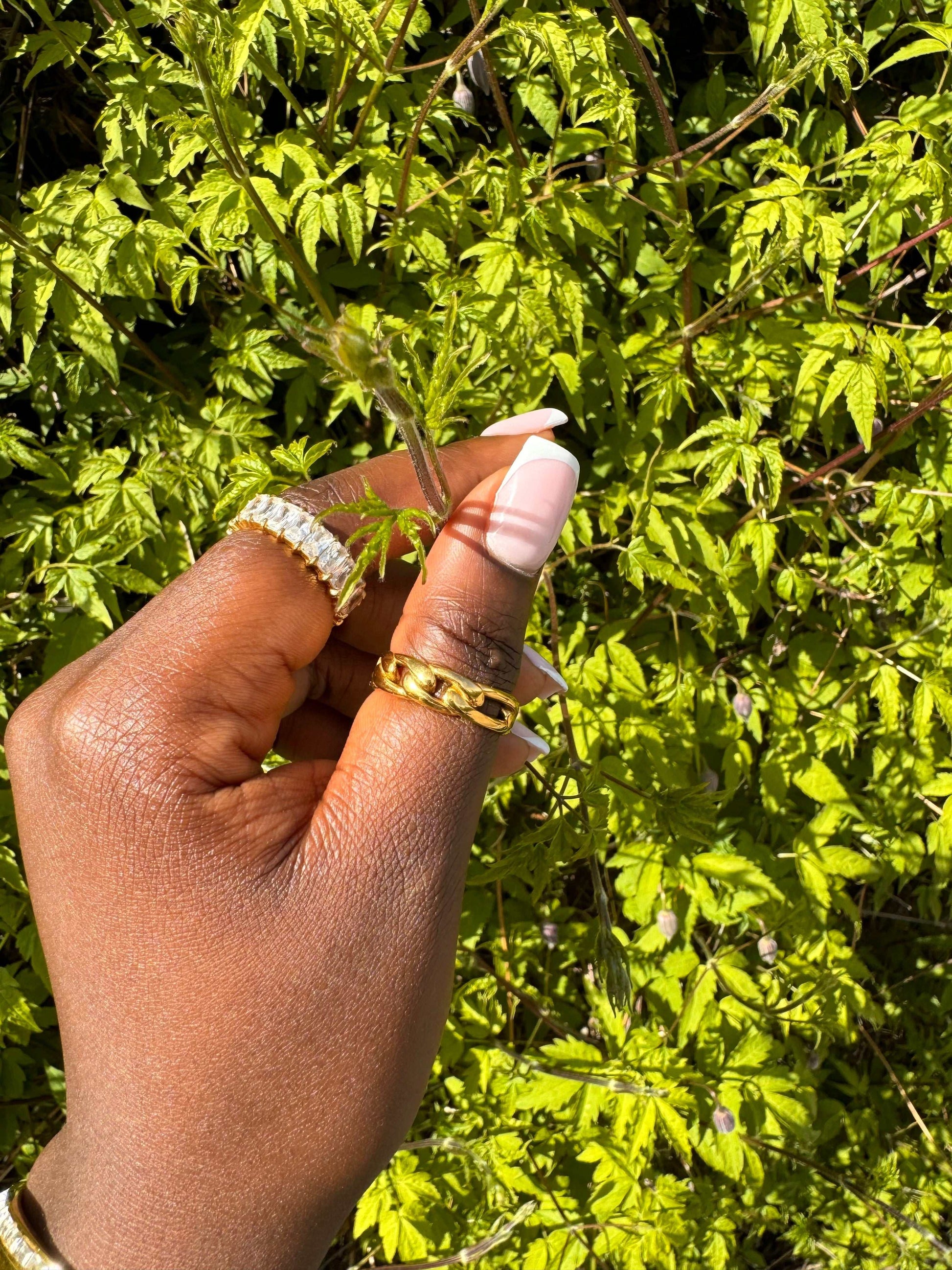 Model wearing the Talia Ring—gold-plated open-link band stacked with other rings, close-up on hands