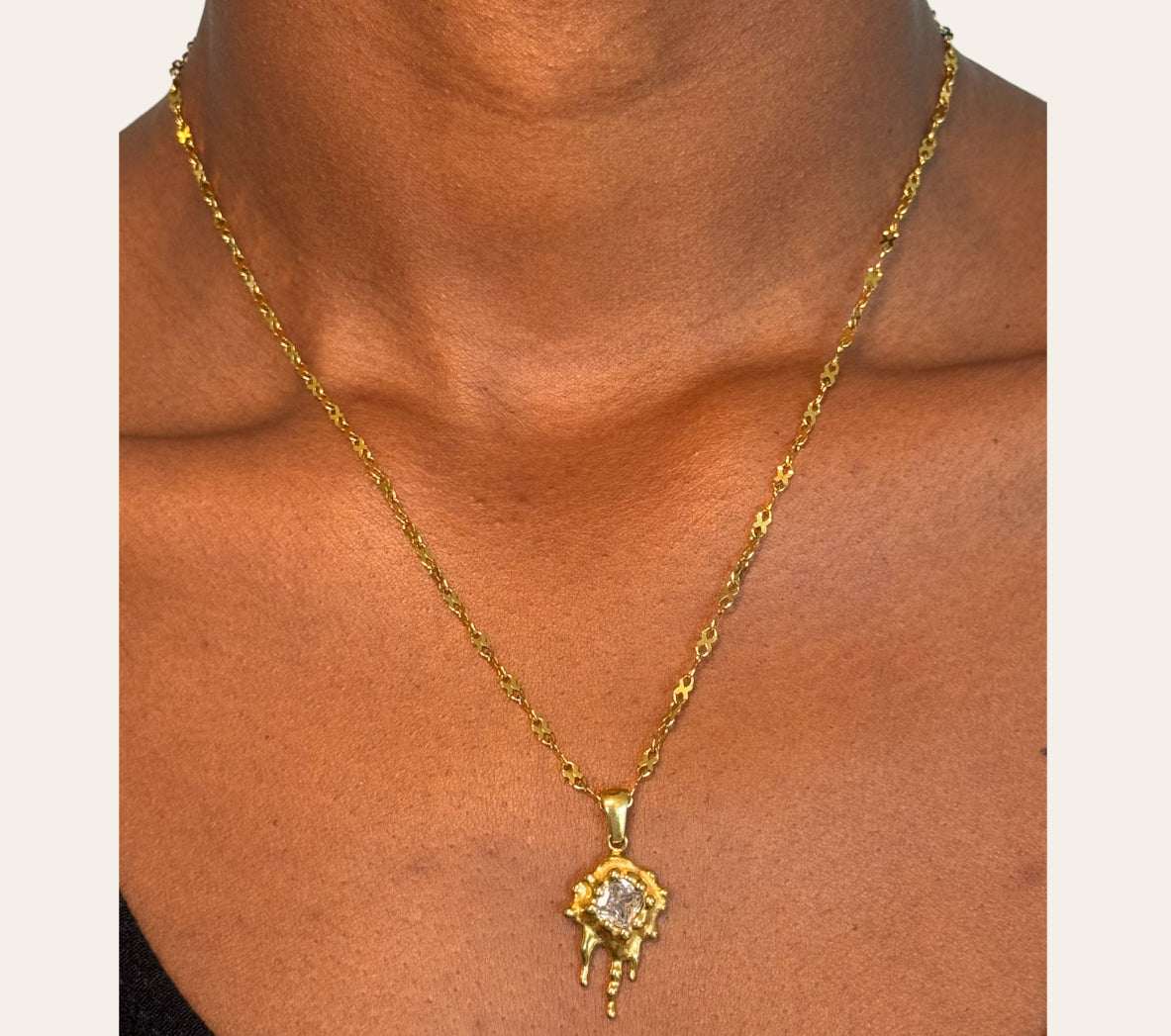 Model wearing Zuri Necklace—molten sun pendant with square-cut zircon, close-up on neckline